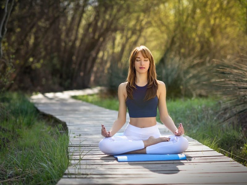 Woman meditating outdoors on a boardwalk in Colorado
