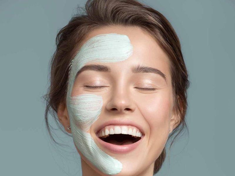 Client smiling with a facial mask applied