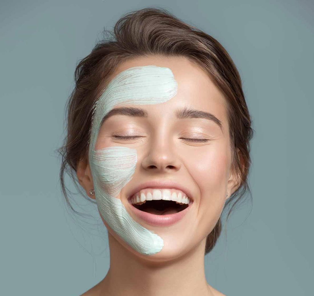 Client smiling with a facial mask applied