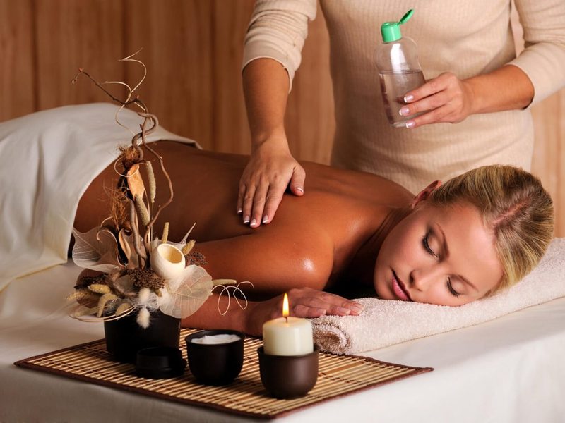 Therapist applying massage oil to a client’s back