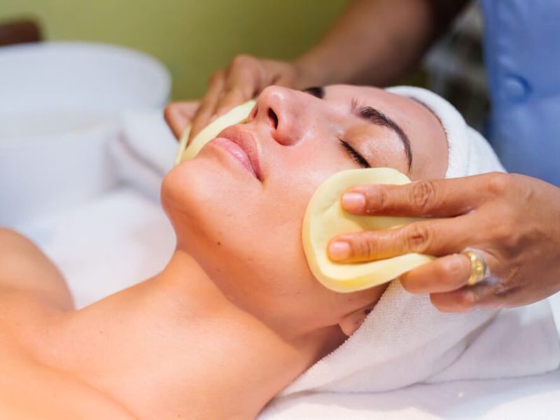 Esthetician applying a chemical peel treatment to a client’s face